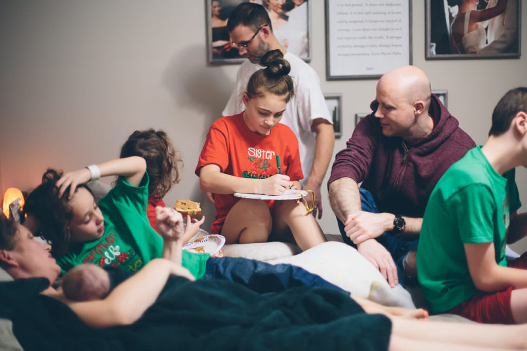 siblings gathered on bed after home birth