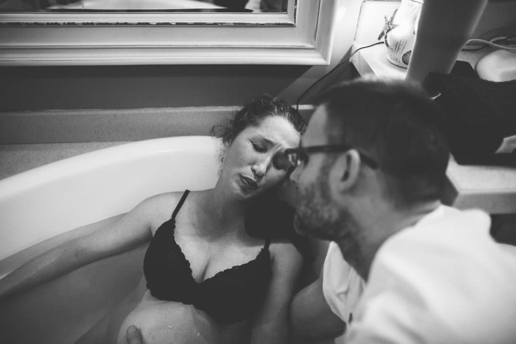 dad helping laboring mom during water home birth