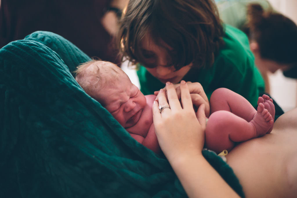 big brother kissing newborn brother after homebirth