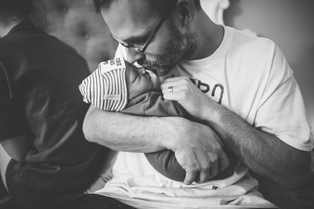 dad kissing new baby black and white