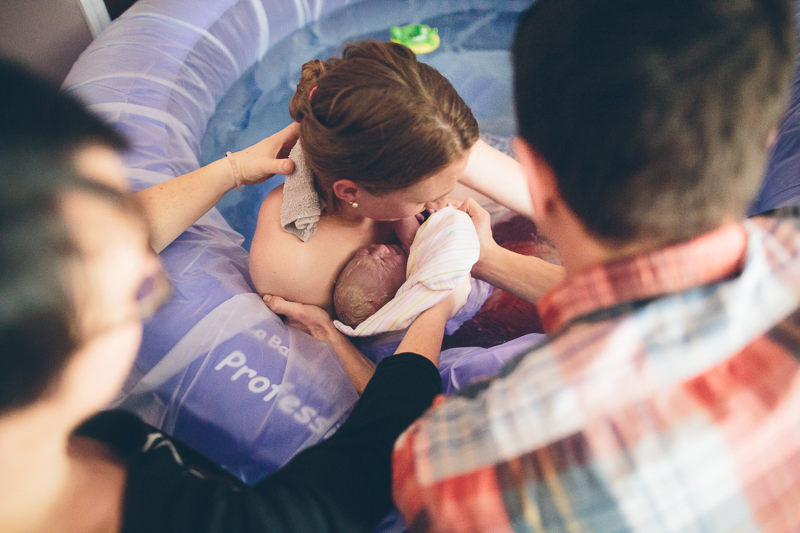 holding just born baby in birth tub