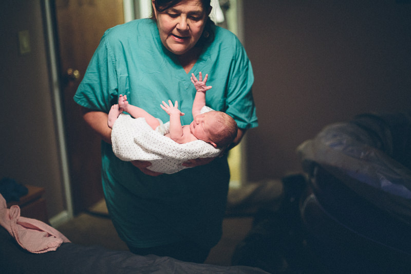 midwife holding newborn for exam