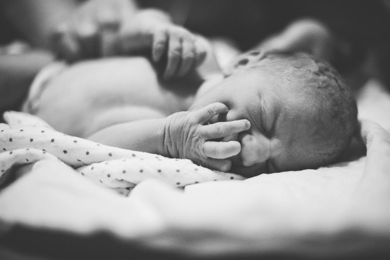newborn with fingers in mouth