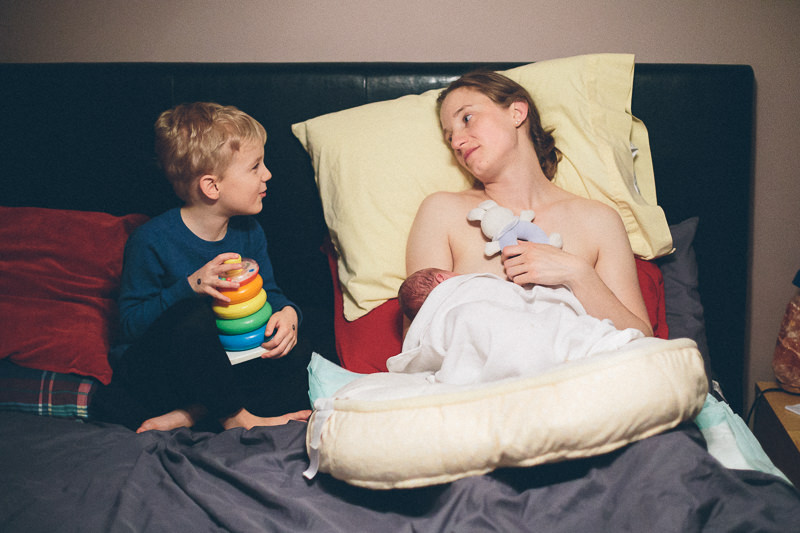 big brother brings toys to newborn sister nursing