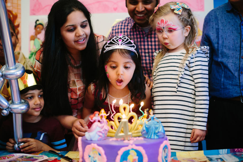 birthday girl blowing out candles on princess cake