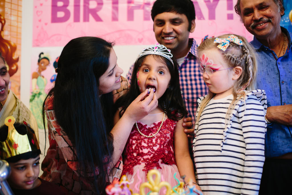 mom feeding birthday girl a piece of cake