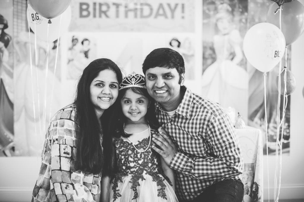 black and white picture of little girl with parents at party