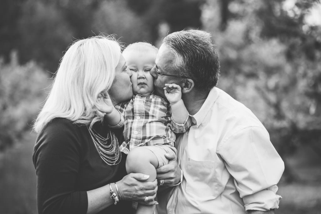 grandma and grandpa kissing baby boy cheeks