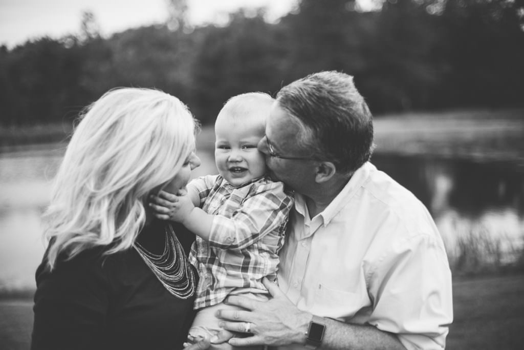 grandson holding grandma face while grandpa kiss his cheek