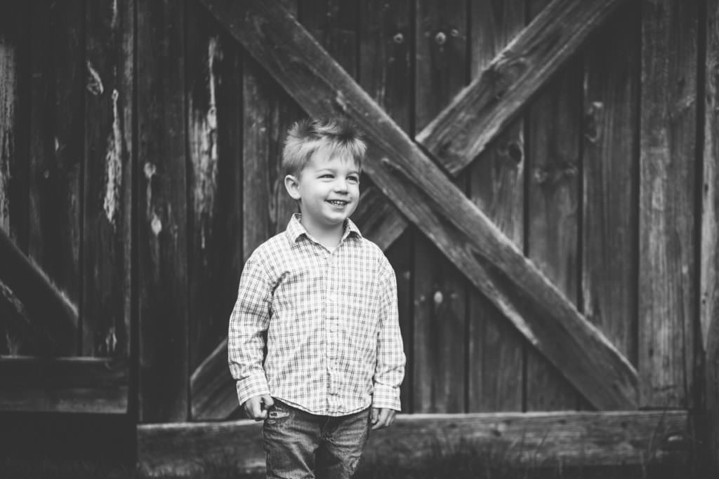 young boy in button up shirt by barn door