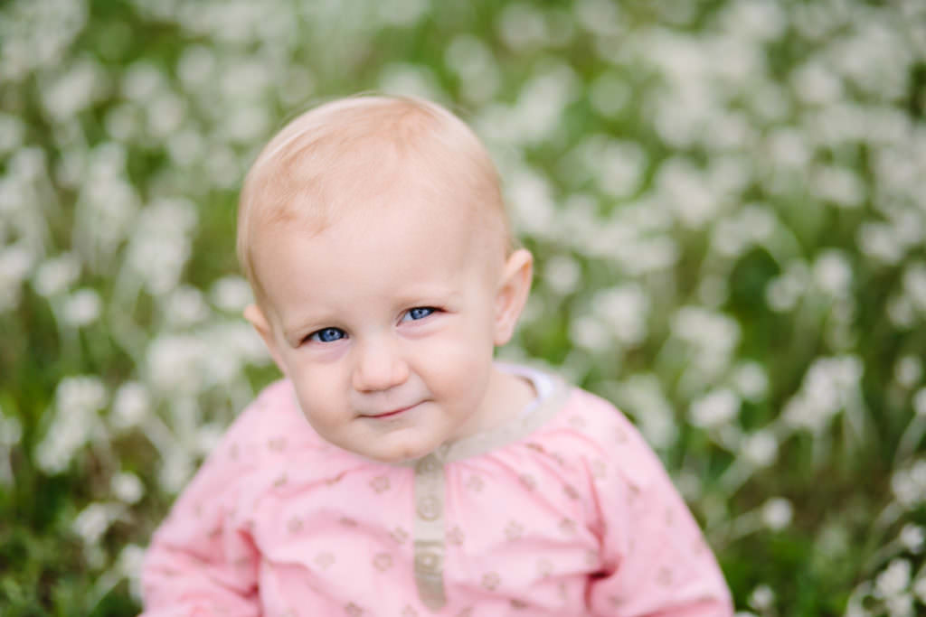 blond hair blue eyed baby sitting in white flowers