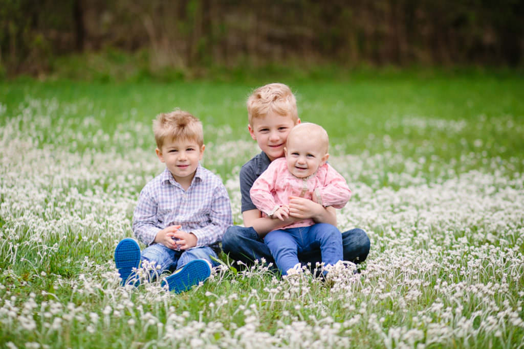 two brothers and baby sister sitting in white flowers