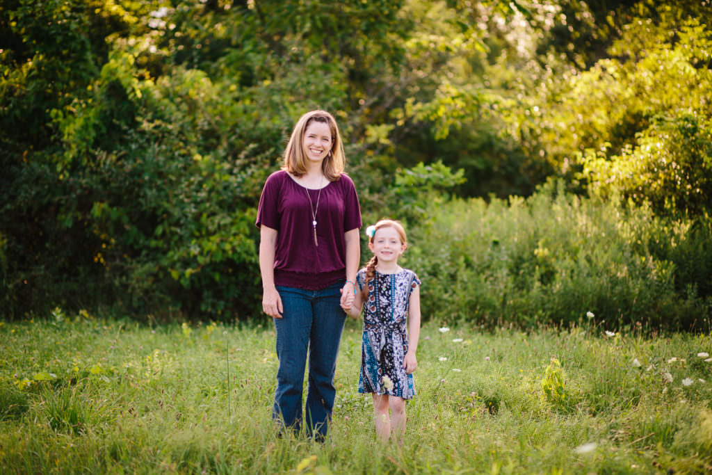 mom and daughter holding hands in field