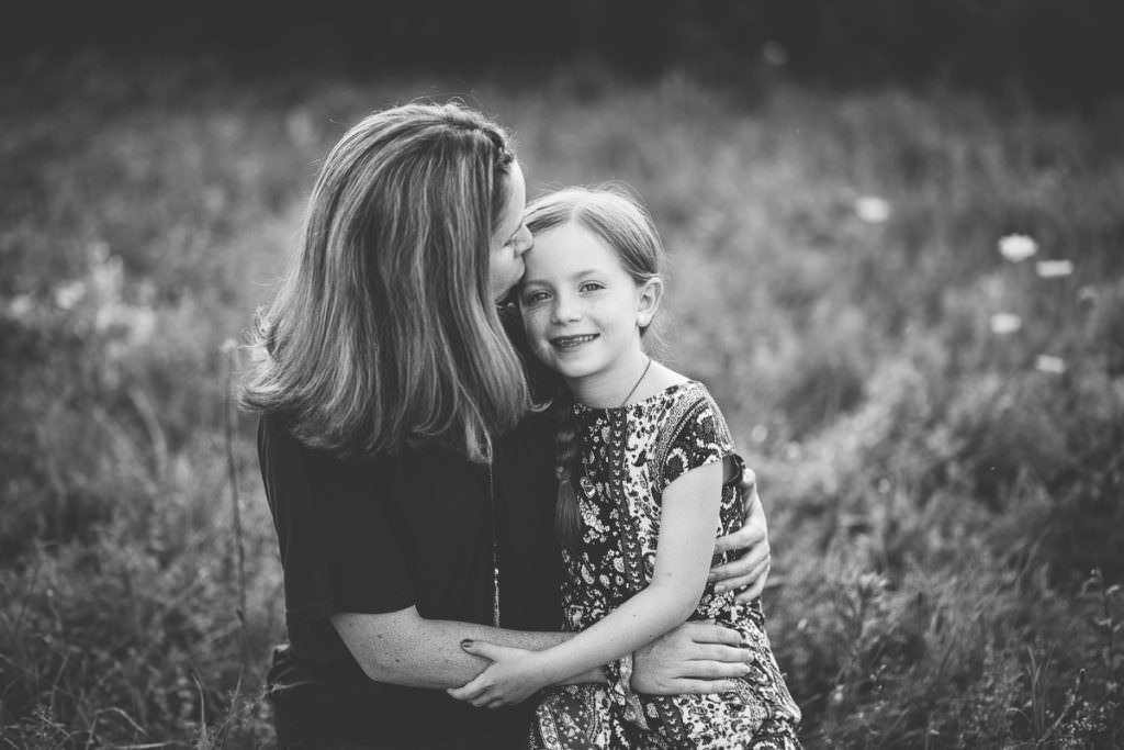 mom kissing daughter on cheek