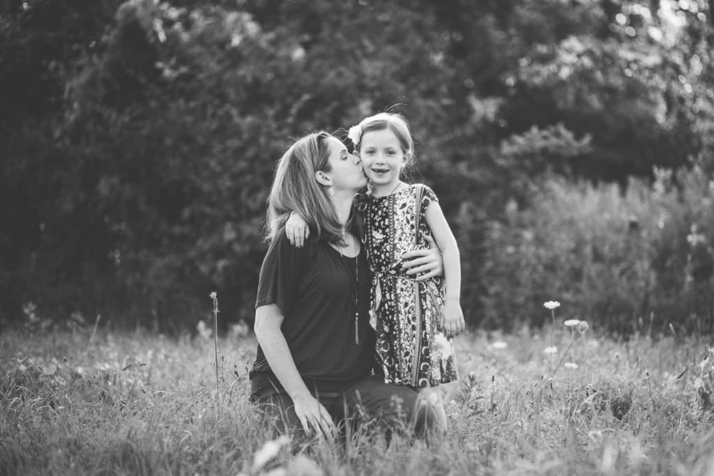 mom kissing young daughter on cheek