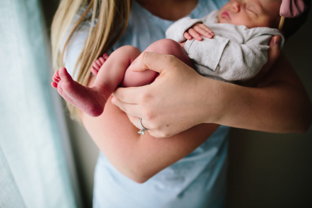 mom hand holding baby feet and legs