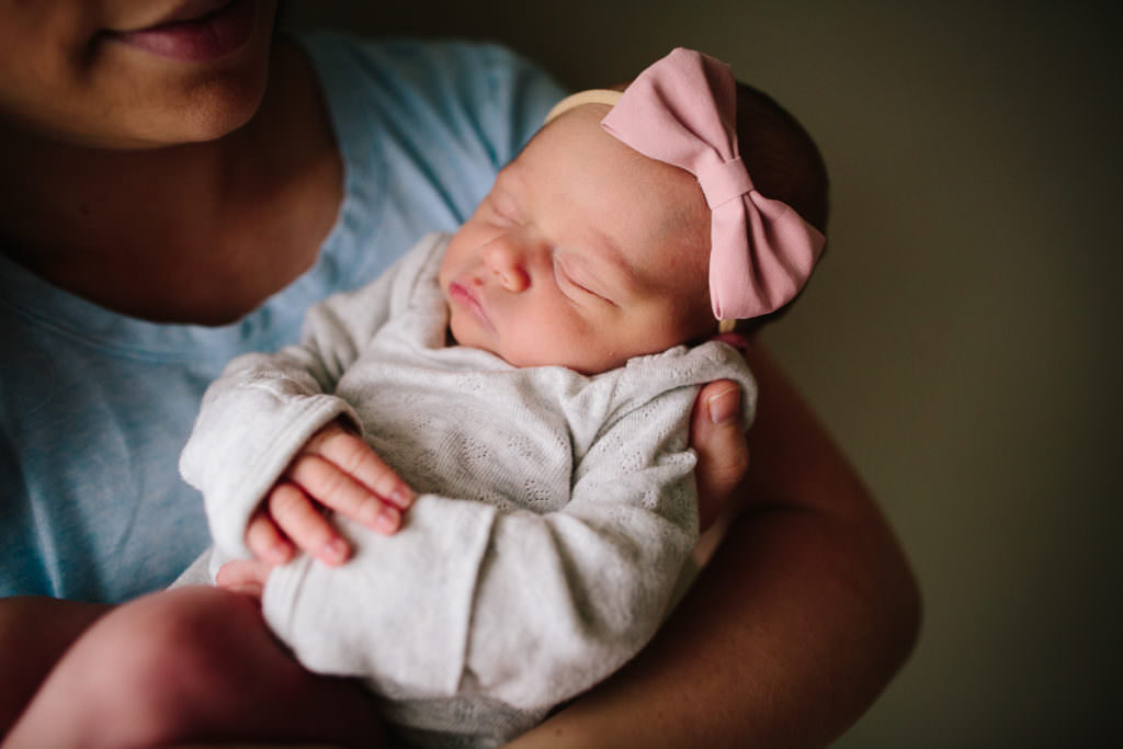 newborn baby girl sleeping in onsie and pink bow