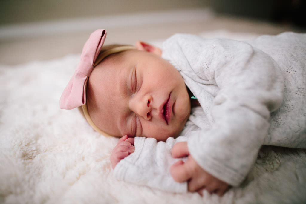 newborn sleeping on white blanket