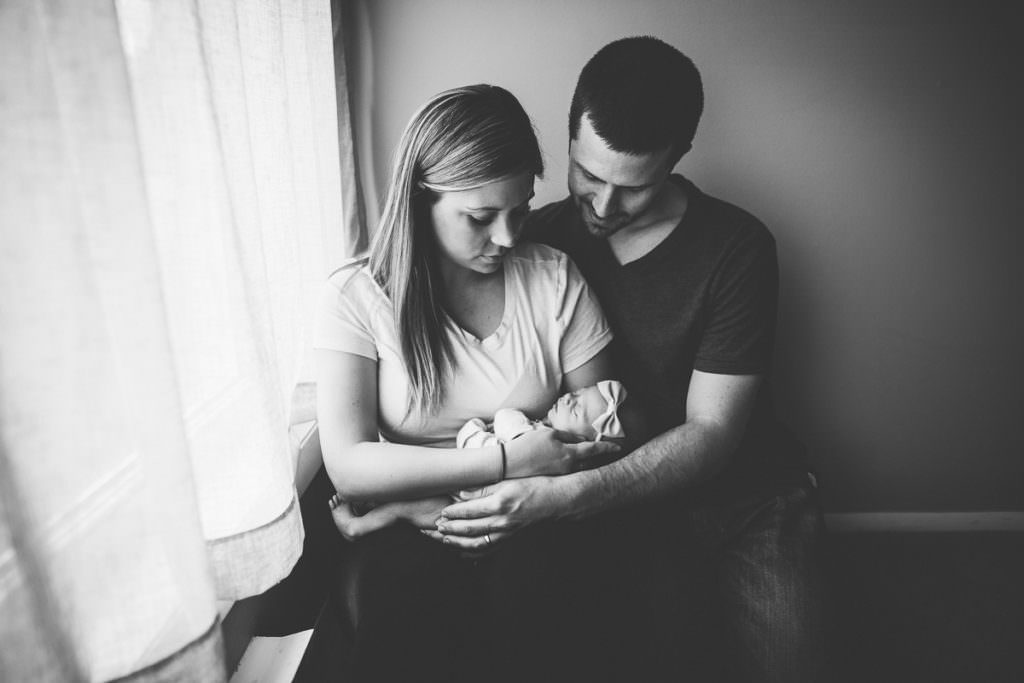 black and white picture parents snuggling newborn