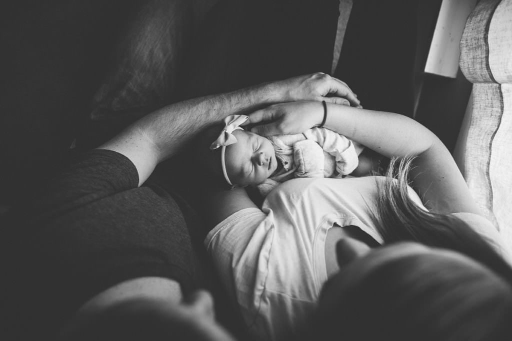 parents arms holding newborn girl