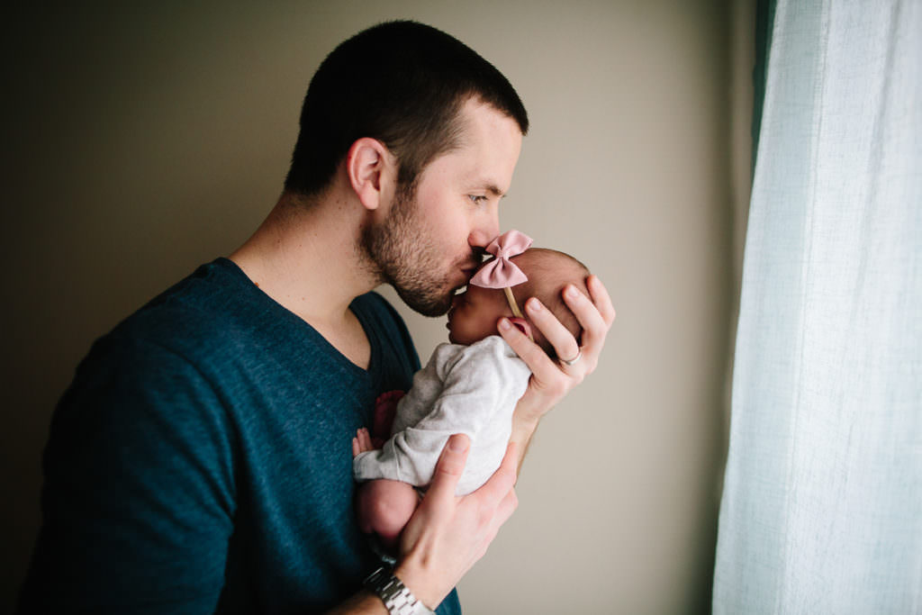dad kissing newborn baby girl forhead