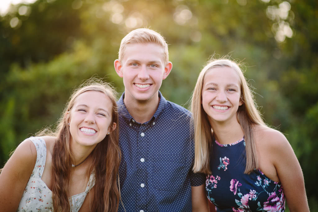 brother and two sisters smiling