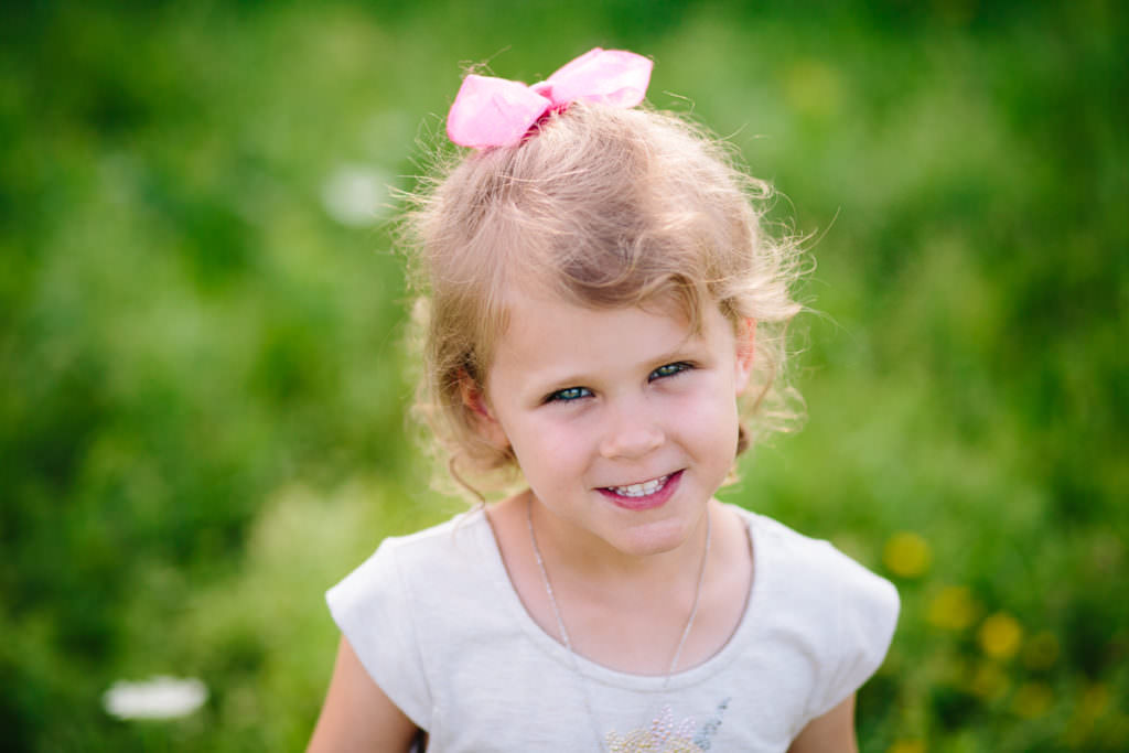 little girl with pink bow green background