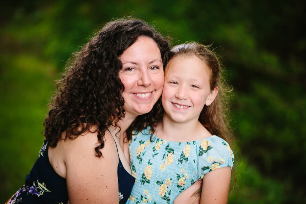 mom with dark curly hair holding young daughter