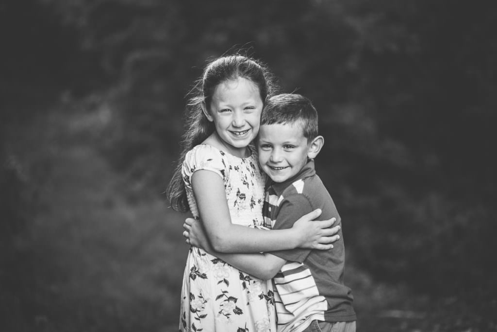 brother and sister hugging black and white