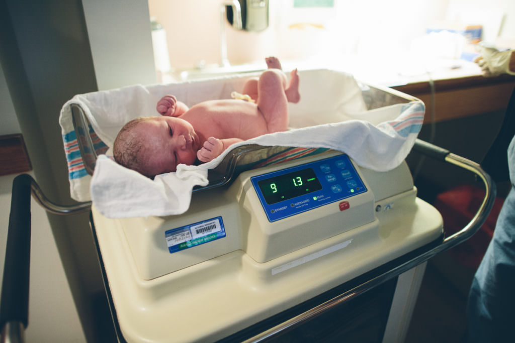 new baby getting weighted after her birth