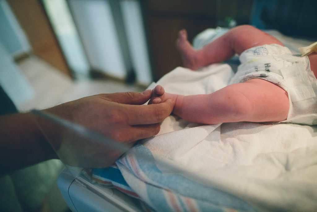 dad holding newborn baby's foot