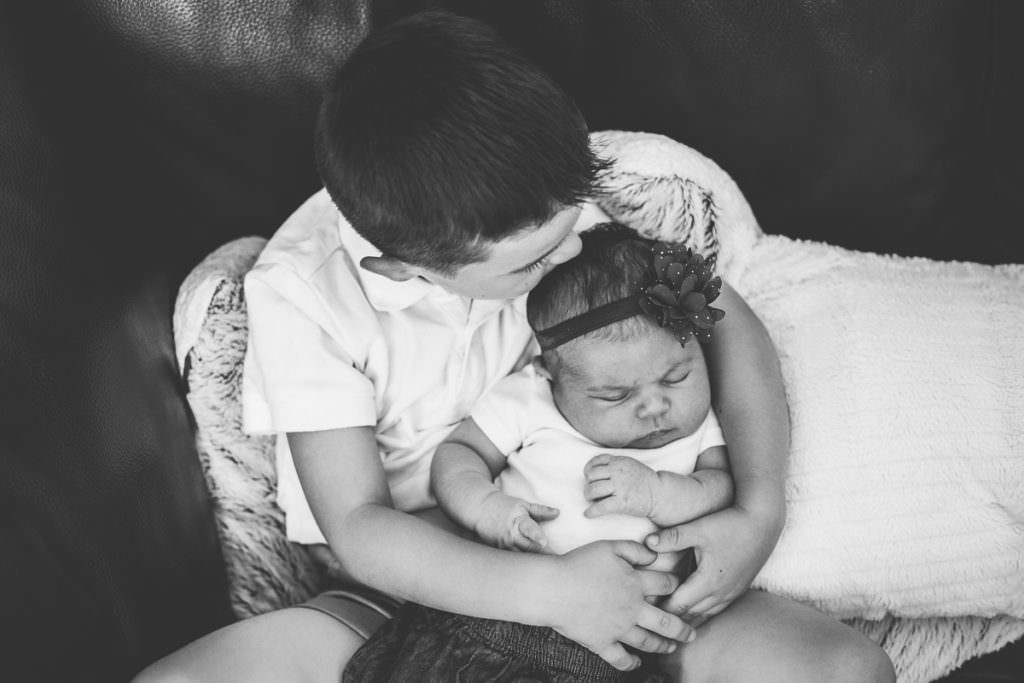 little boy kissing newborn baby sister on her head