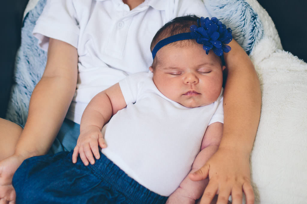 sleeping newborn baby girl on brother lap