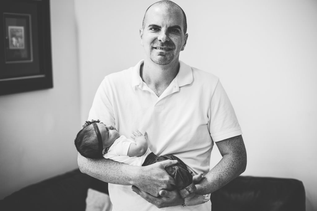 dad holding newborn daughter in his home