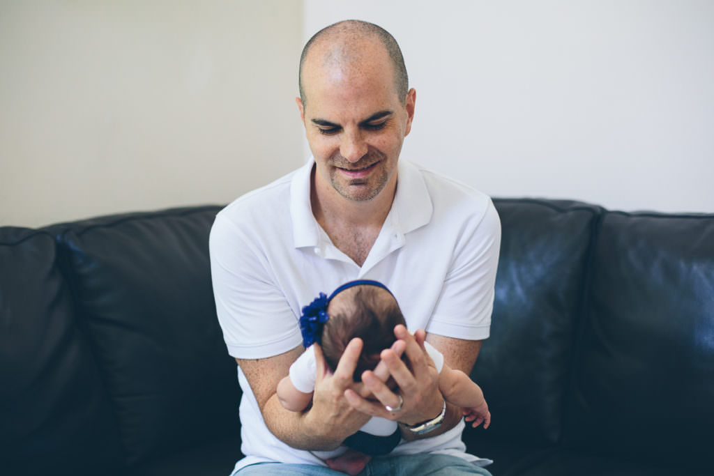dad holding and looking at new baby daughter