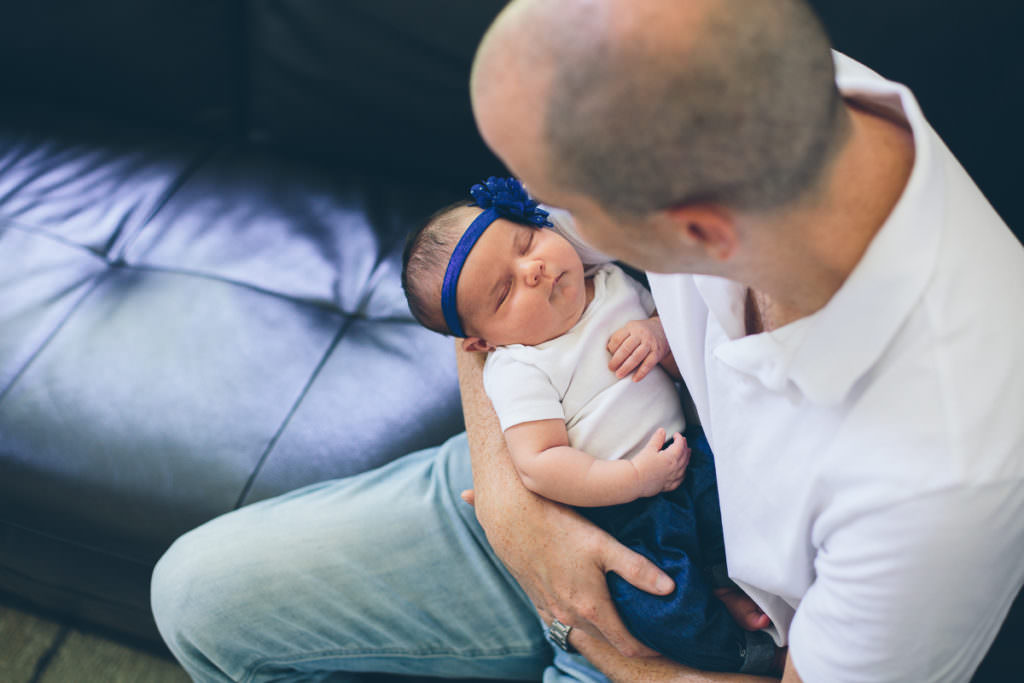 dad holding baby girl on couch in his home