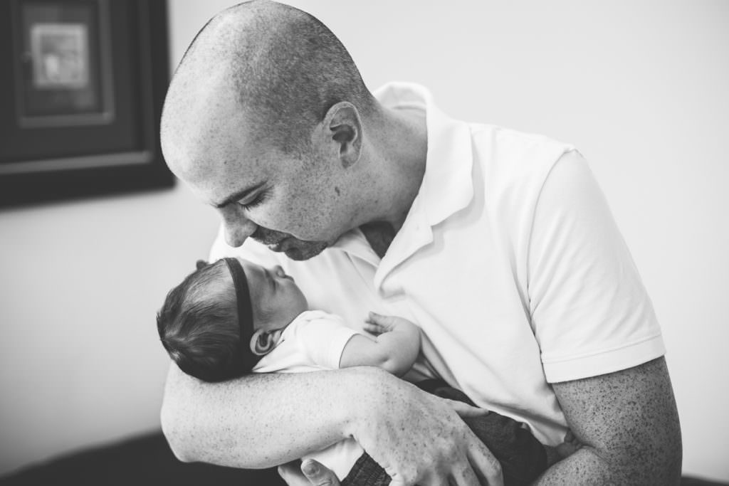 dad giving newborn baby girl a kiss on the head
