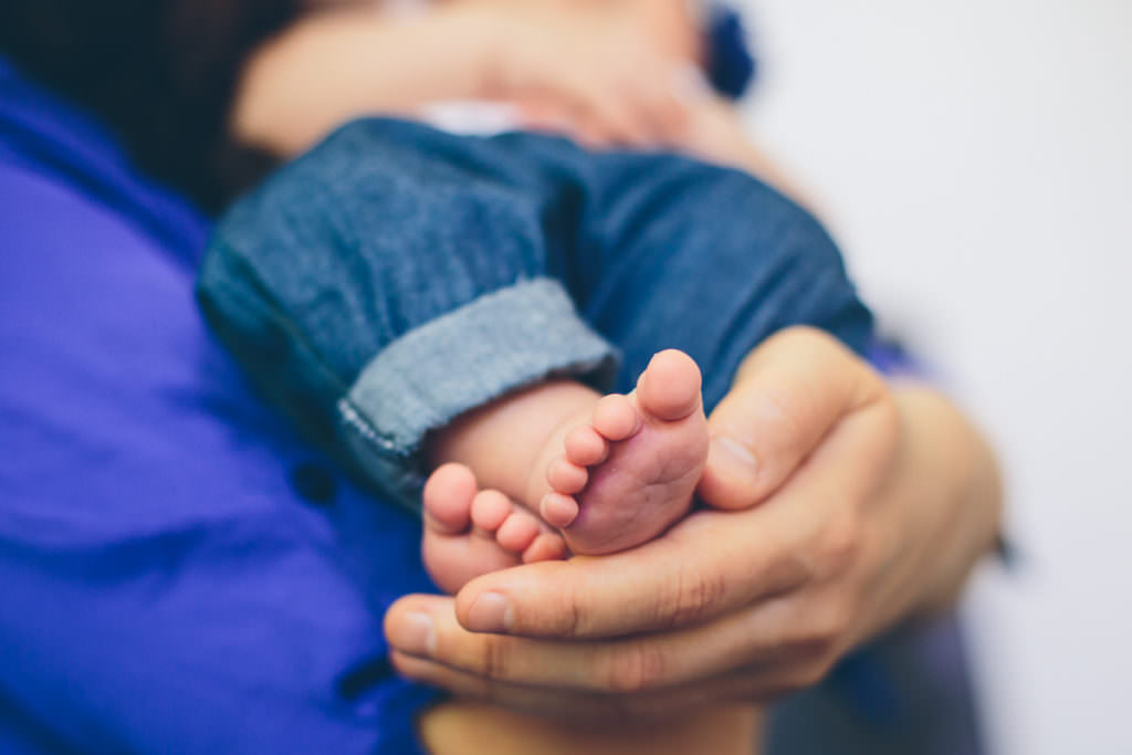 mom holding newborn baby feet
