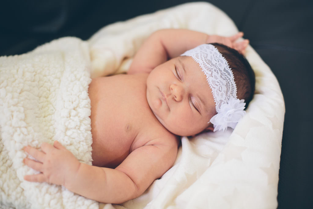 newborn baby girl wrapped in white blanket and headband