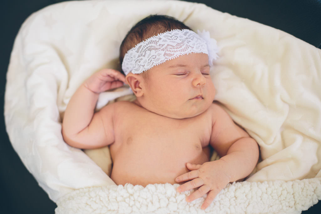 newborn baby girl lying on white blanket