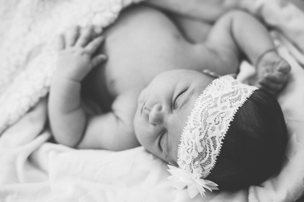 black and white picture of newborn girl with flower headband