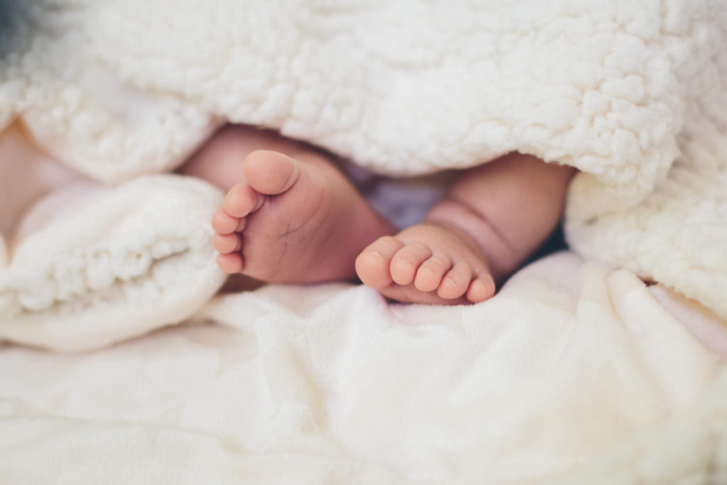 newborn baby feet in white fluffy blanket