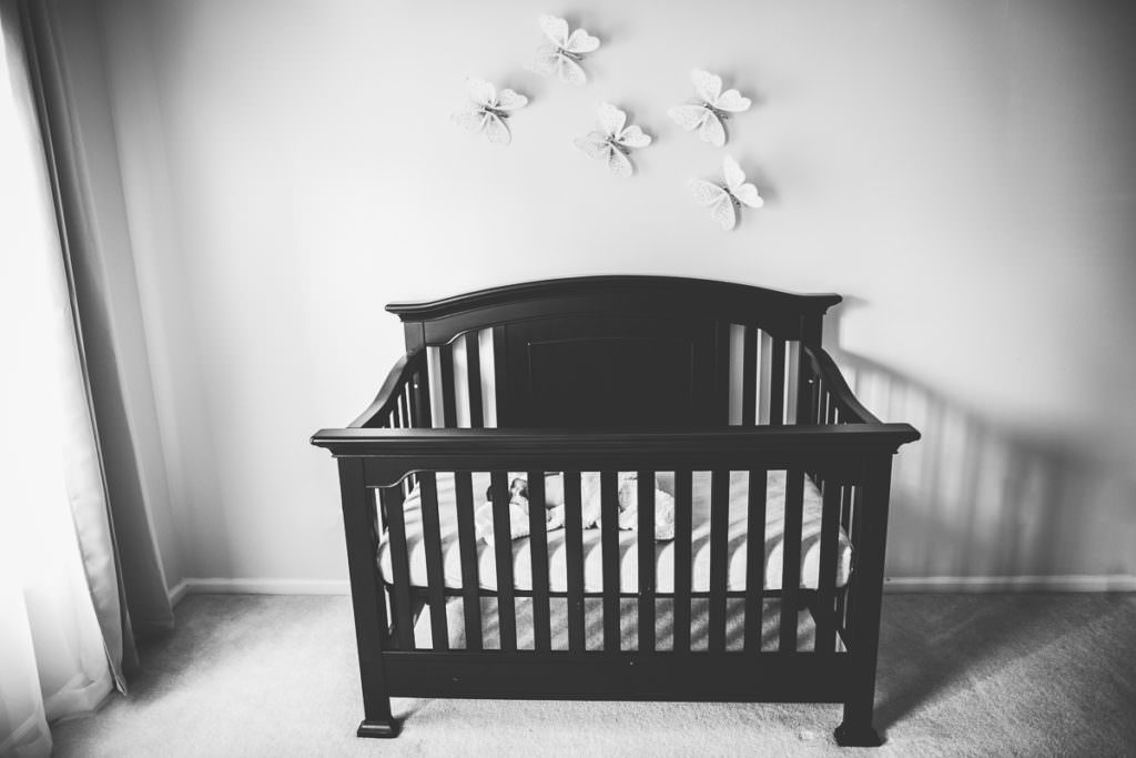 newborn girl in crib with butterfly decorations