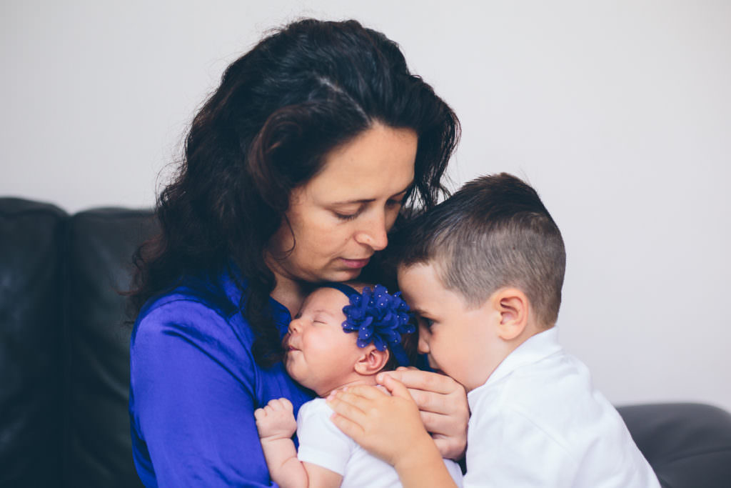 mom holding newborn daughter son snuggling