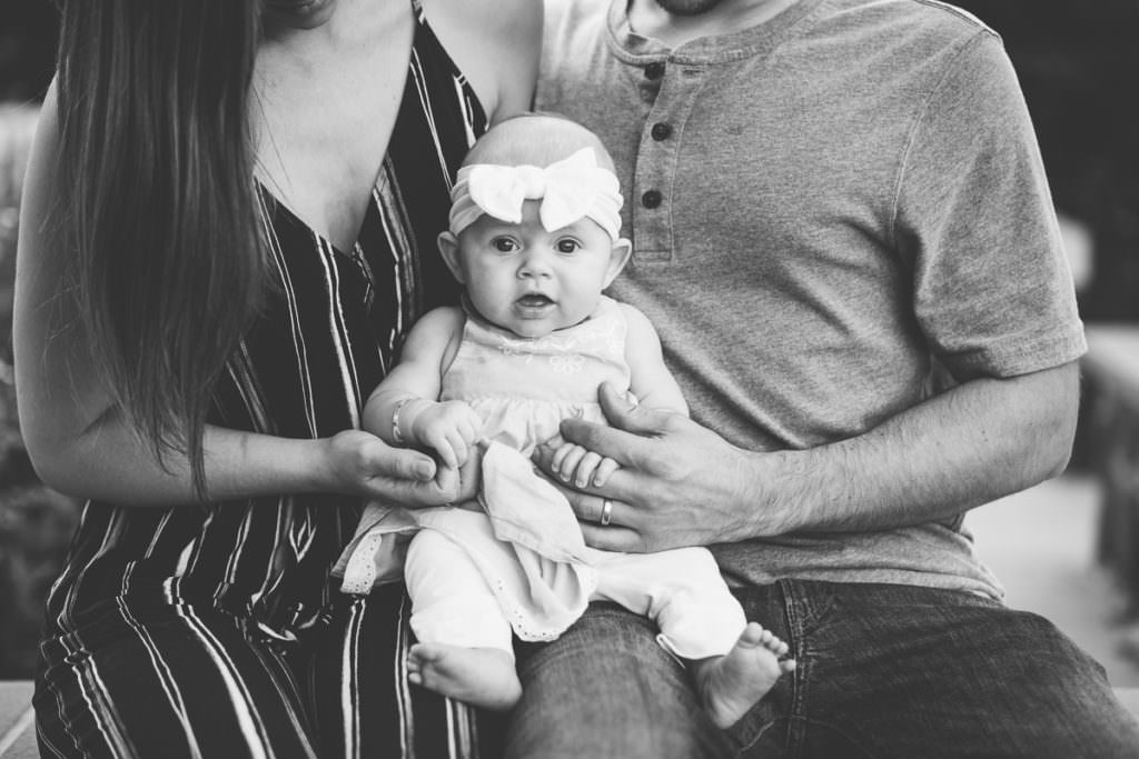 mom and dad holding baby girl on lap