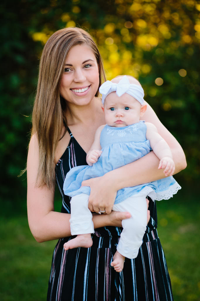 mom holding baby girl with white bow