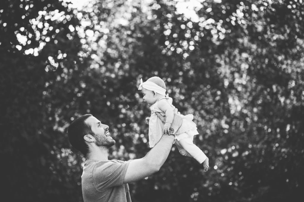 dad holding baby girl to the sky
