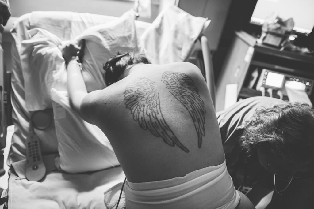 back of laboring mom with angel wings tattooed on her back