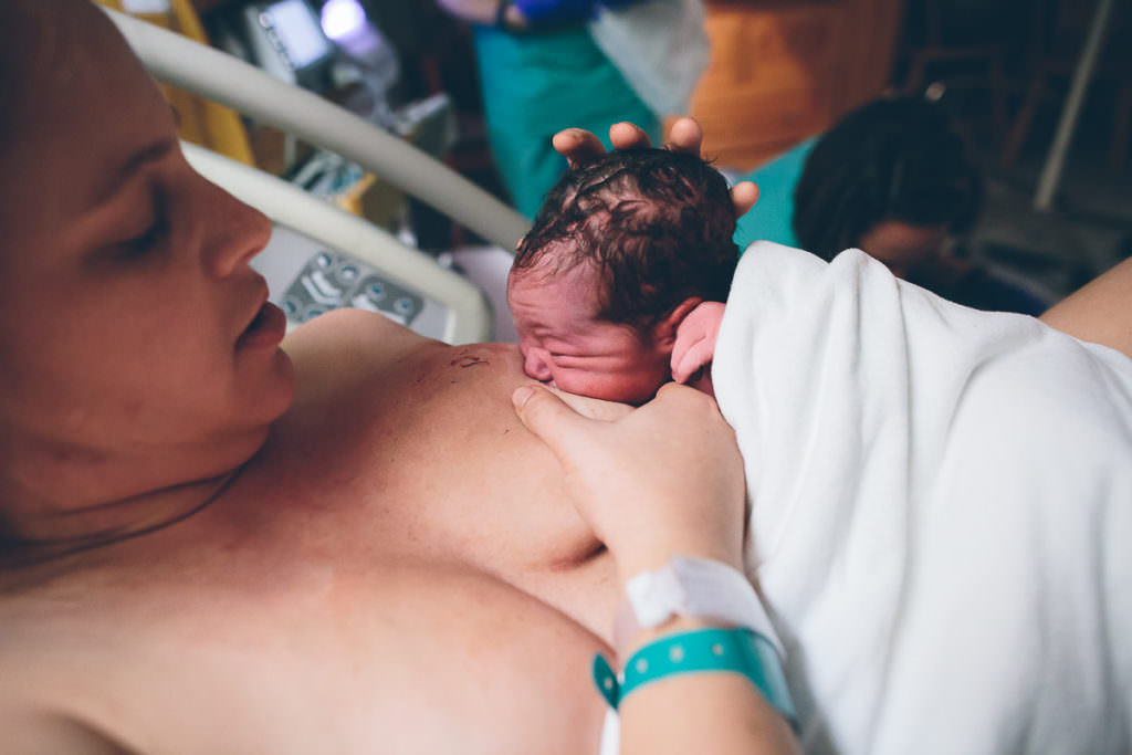 mom holding breast in c shape and breastfeeding her newborn baby