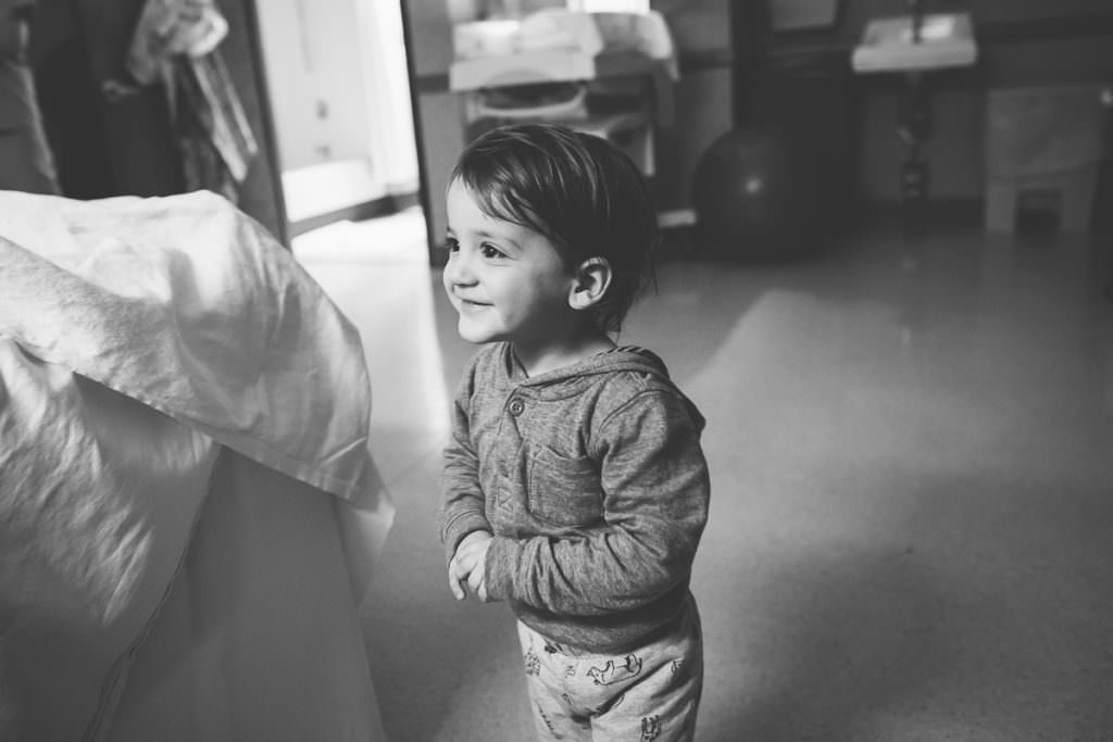 black and white picture of little boy seeing baby brother for the first time